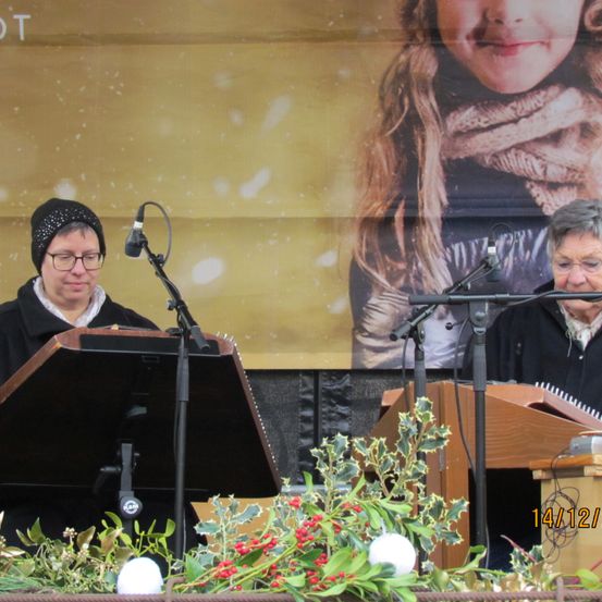 Bild enthält, Adult, Female, Person, Woman, Concert, Microphone, Face, Group Performance, Musical Instrument, Flower Arrangement