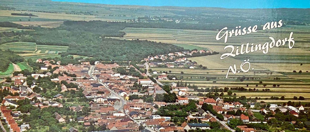 Luftaufnahme von Gruisse Zilling, einem kleinen Dorf mit vielen Häusern und Gebäuden, umgeben von grünen Bäumen und Gras, mit einem großen Feld im Hintergrund.