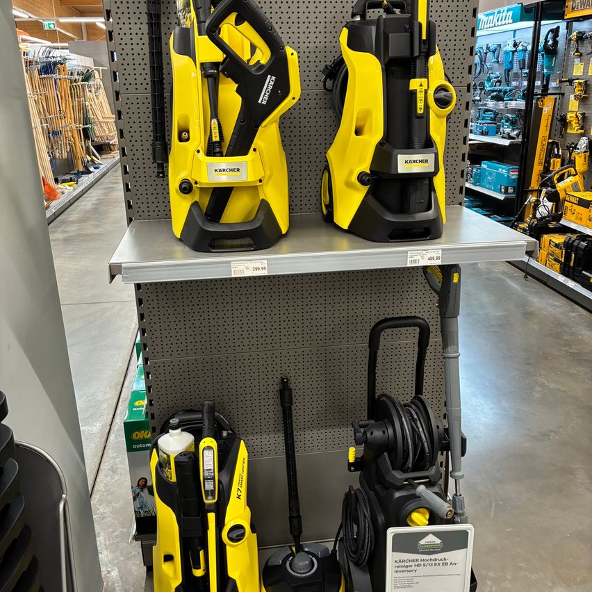 A Kärcher high-pressure washer is on display in a store, with another model and tools in the background.