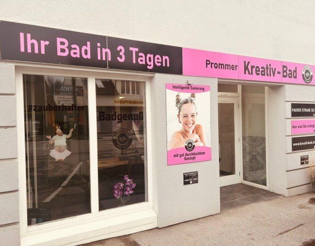 Fassade eines Spas mit einem Schild, das 'Ihr Bad in 3 Tagen' anzeigt. Eine lächelnde Frau ist auf einem Plakat an der Wand abgebildet.