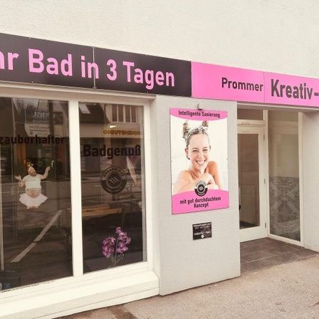 Fassade eines Spas mit einem Schild, das 'Ihr Bad in 3 Tagen' anzeigt. Eine lächelnde Frau ist auf einem Plakat an der Wand abgebildet.