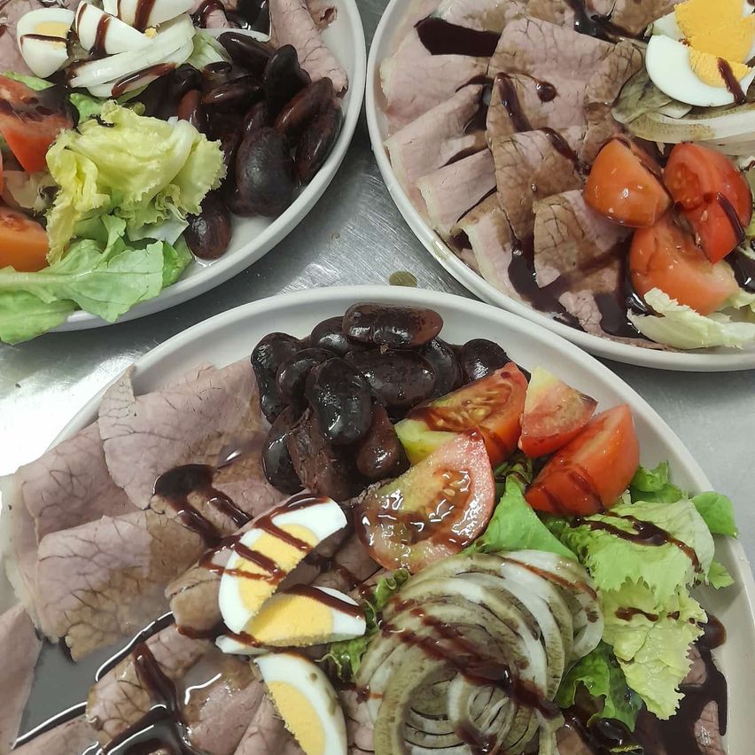 Drei Teller mit einer Mahlzeit aus Fleisch, Eiern und Gemüse. Jeder Teller hat eine Mischung aus geschnittenem Fleisch, Eiern und Gemüse, einschließlich Tomaten, Zwiebeln und schwarzen Bohnen.