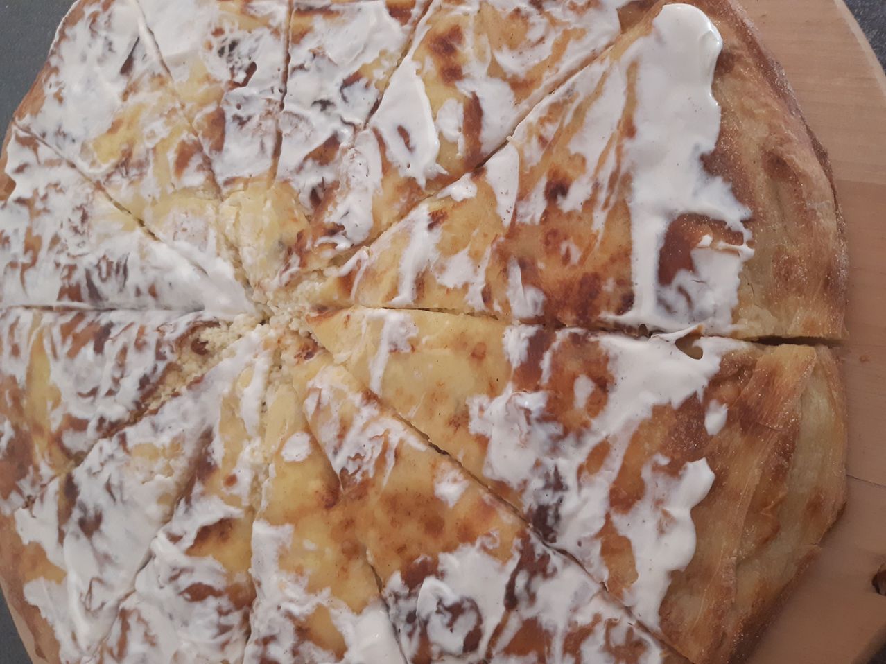 Ein kreisförmiges Gebäck mit Zimt und Zucker obenauf, in Stücke geschnitten, mit weißer Glasur darüber gegossen.