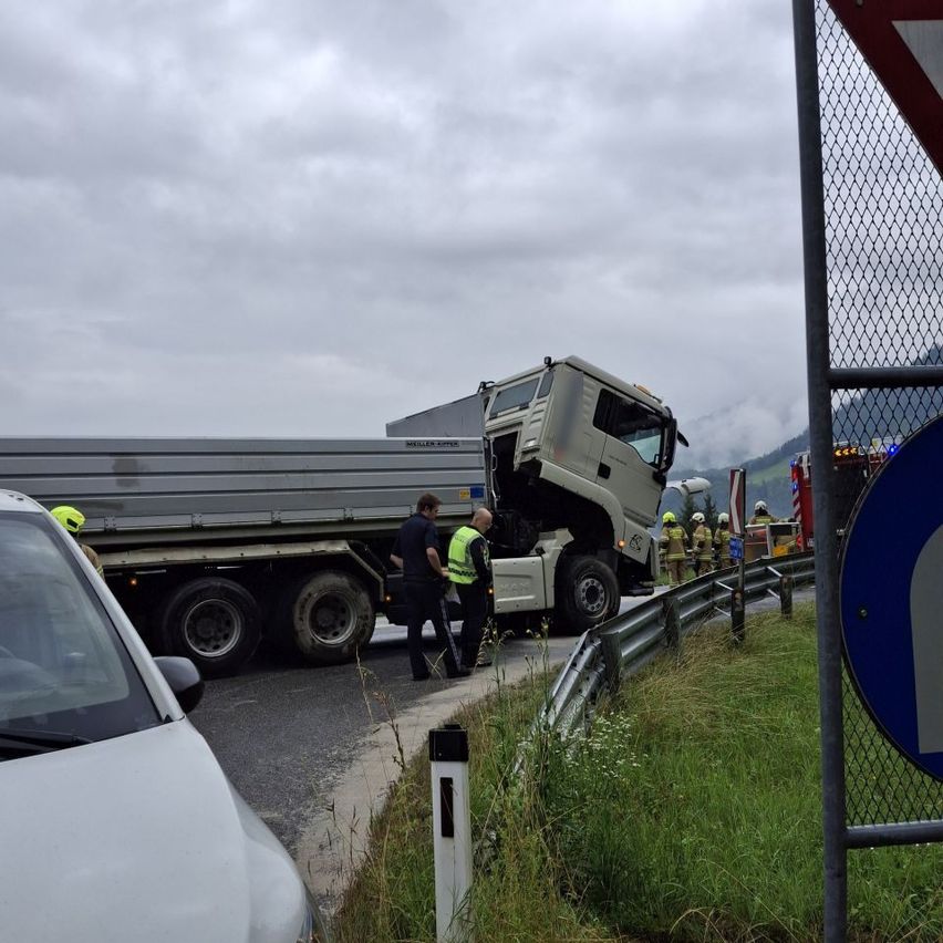 Ein Lkw-Unfall auf einer Straße mit Rettungskräften. Ein weißer Wagen ist in der Nähe geparkt.