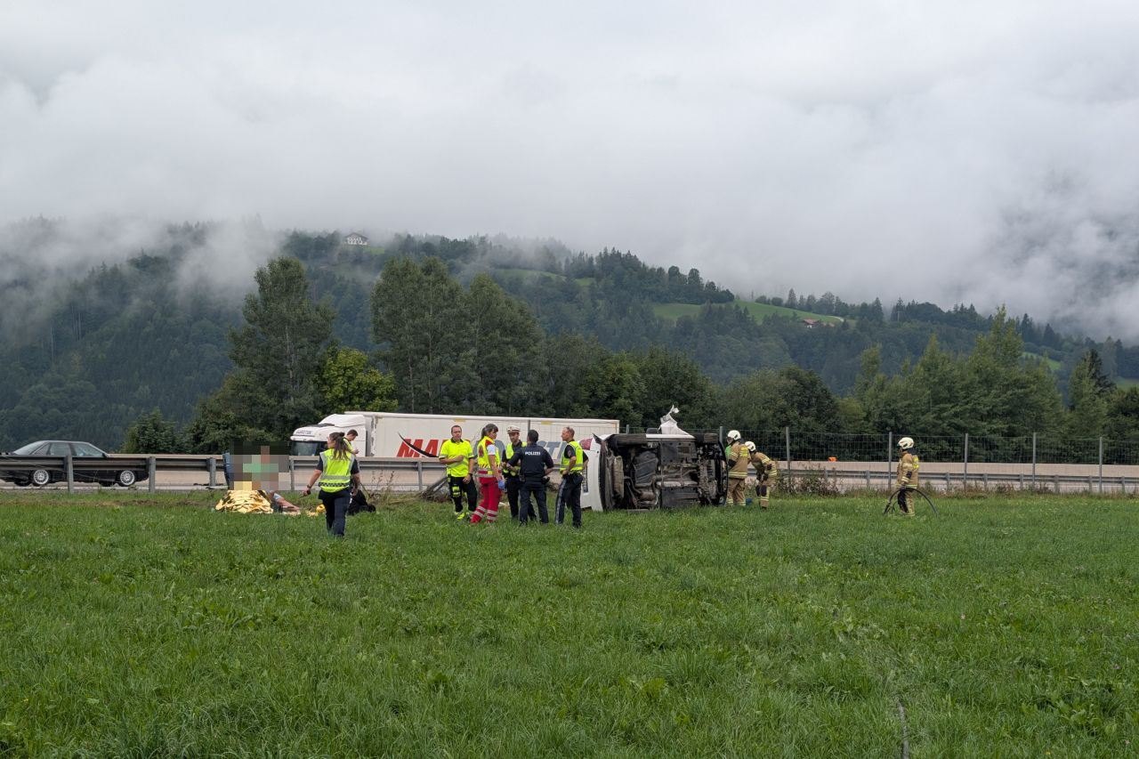 Unfall mit umgekipptem Lkw und Rettungskräften auf einer Wiese in den Bergen