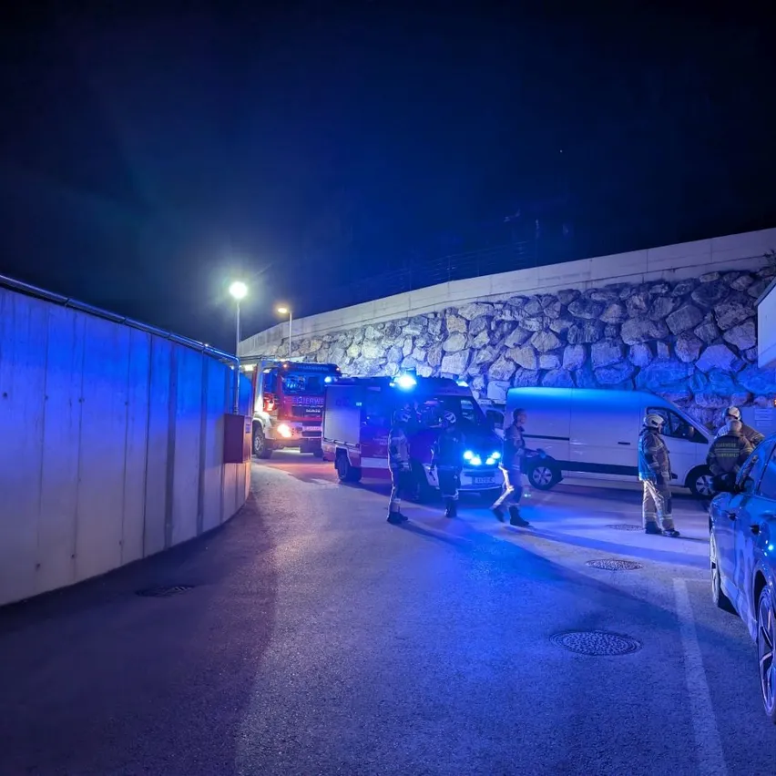 Notfallfahrzeuge sind nachts auf einer Straße geparkt, mit Beamten, die herumlaufen.