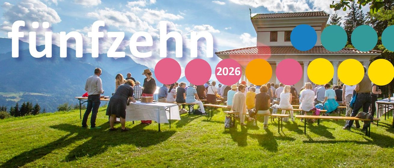Eine Gruppe von Menschen sitzt auf Bänken im Freien, mit einem Gebäude und Bergen im Hintergrund. Das Jahr 2026 ist prominent angezeigt.