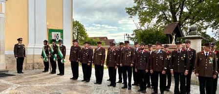 Eine Reihe uniformierter Männer steht vor einem Kirchengebäude an einem bewölkten Tag.