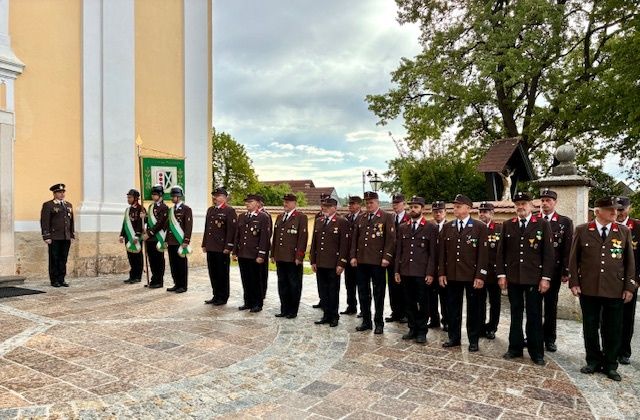 Eine Reihe uniformierter Männer steht vor einem Kirchengebäude an einem bewölkten Tag.
