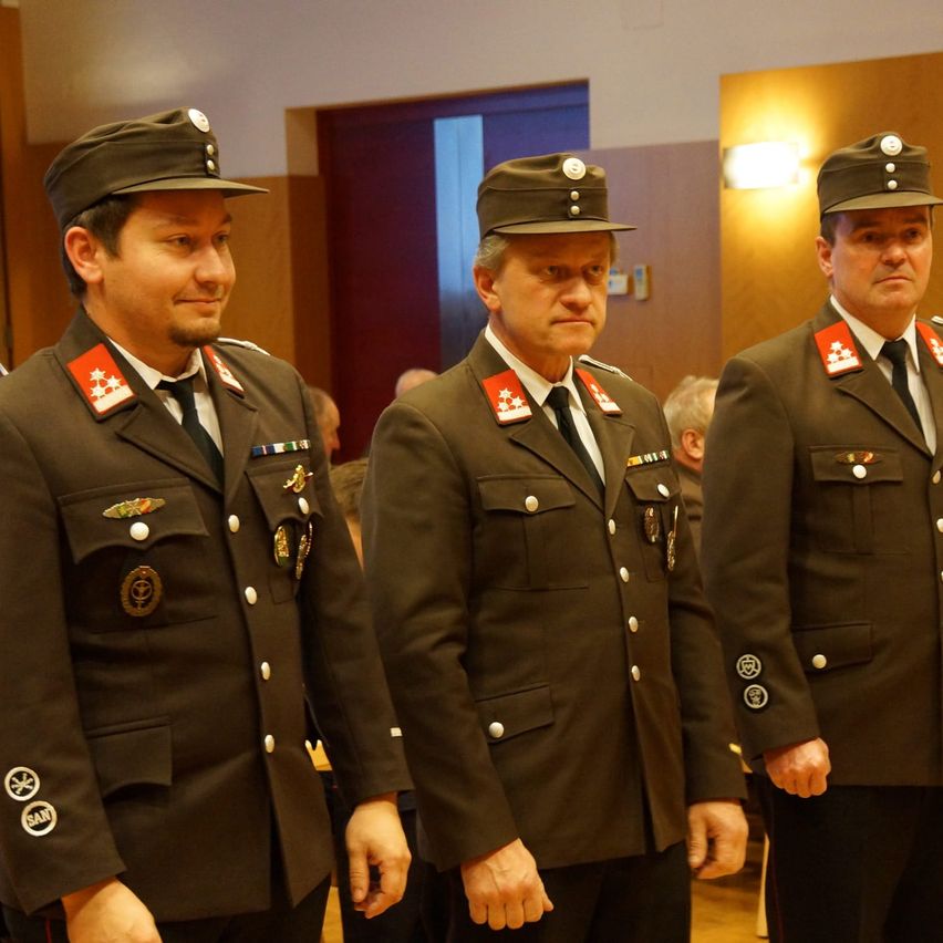 Drei Männer in Militäruniformen stehen nebeneinander, möglicherweise bei einer formellen Veranstaltung. Sie schauen in verschiedene Richtungen.