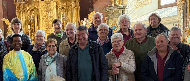 Eine Gruppe von Menschen posiert für ein Foto in einer Kirche mit kunstvollen goldenen Altären und Statuen im Hintergrund.