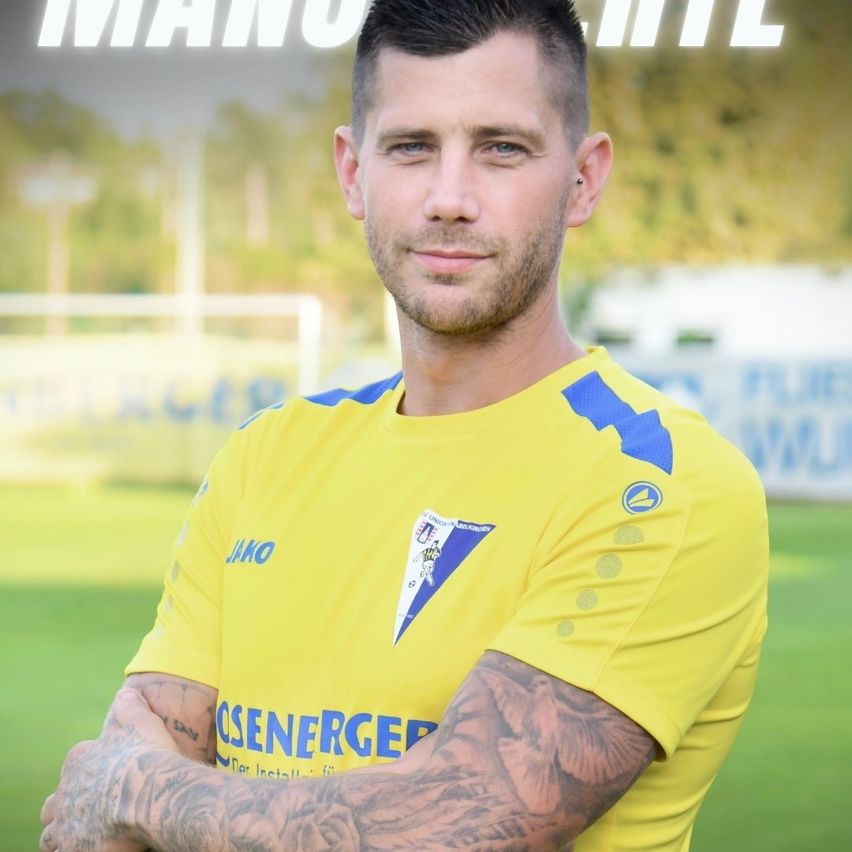 Ein Mann mit Tattoos auf den Armen steht auf einem Fußballfeld und trägt ein gelbes Trikot.