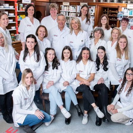 Eine Gruppe von Fachleuten in weißen Laborkittel, möglicherweise Apotheker, posiert für ein Foto in einer Apotheke.