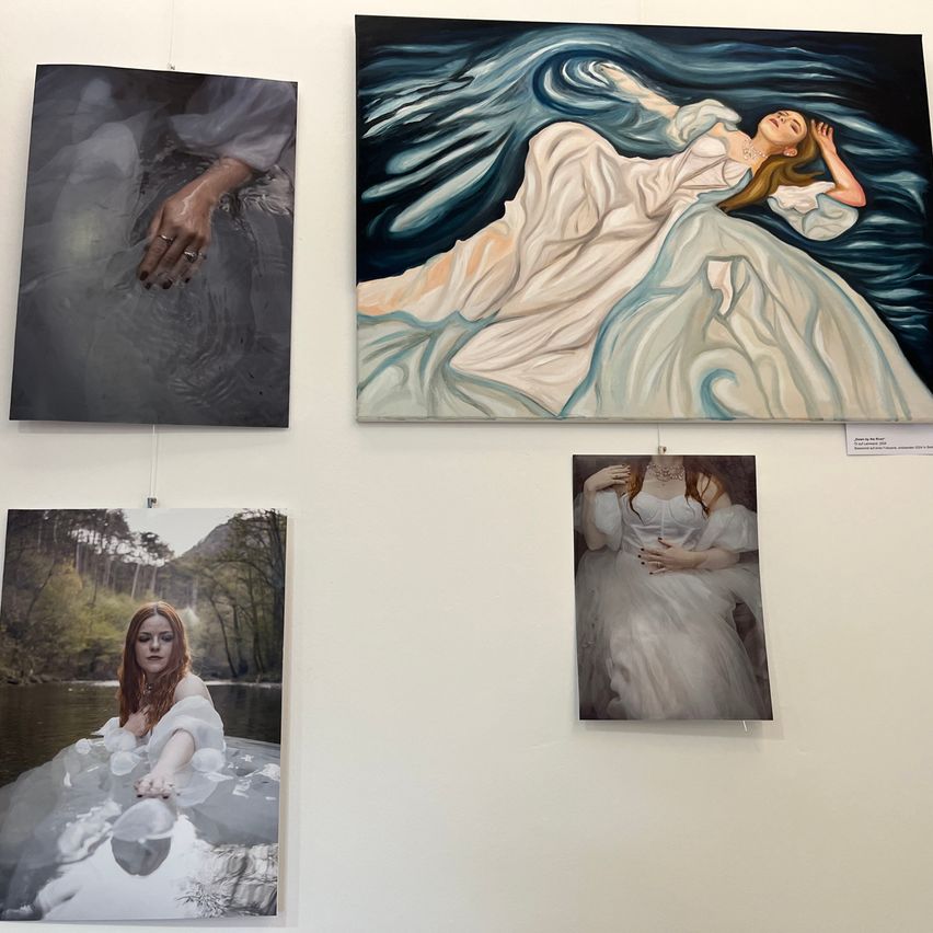An einer weissen Wand hängen fünf Gemälde, darunter eines von einer Frau, die in Wellen liegt, eines von einer Frau mit rotem Kopf und drei weitere Gemälde.