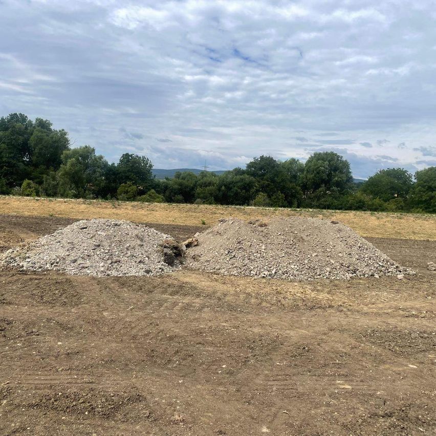 Schutt und Erde auf Baustelle vor bewaldeter Hügellandschaft