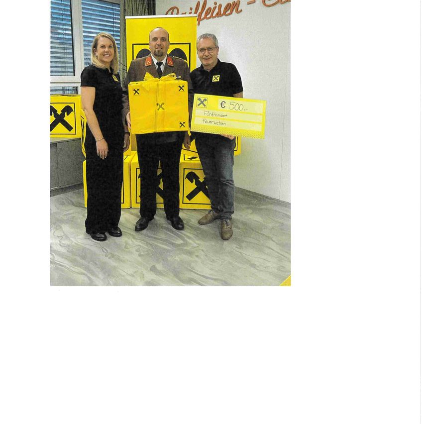 Drei Personen stehen nebeneinander und halten eine gelbe Geschenkbox und einen Scheck. Der Scheck hat einen Betrag von 500 Euro. Sie stehen vor einem gelben Banner.