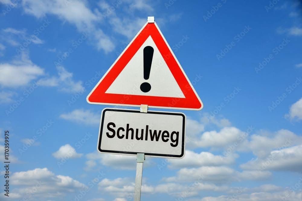 A triangular warning sign with an exclamation mark is above a rectangular sign that reads 'Schulweg'. The sky is blue with scattered clouds.