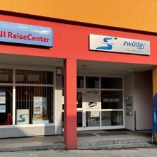 Der Eingang des TUI ReiseCenter-Gebäudes zeigt ein blaues Schild mit weißen Buchstaben, auf dem 'TUI ReiseCenter' steht. Über dem Eingang befindet sich ein weiteres Schild mit dem Wort 'zwolfer' in Blau.