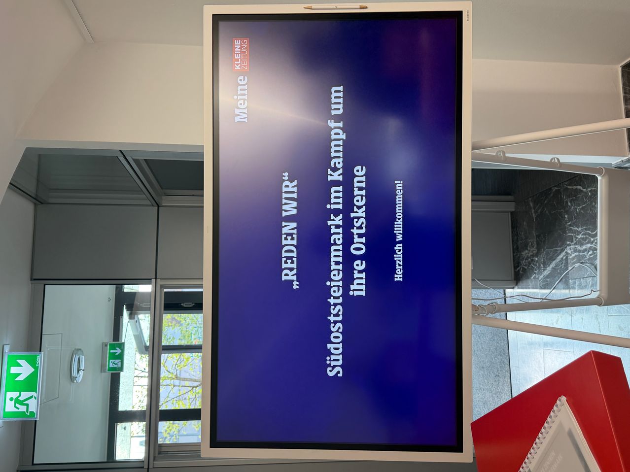 A blue screen with white text reading 'REDEN WIR.' 'Sidostermark im Kampf um ihre Ortskerne' with 'Herzlich willkommen!' below. It appears to be an advertisement.