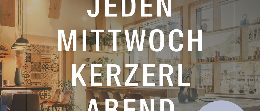 Ein Restaurantinnenraum mit Holzbalken, einem runden Tisch und Stühlen. Der Text 'JEDEN MITTWOCH KERZERL ABEND' ist prominent angezeigt. Ein Schild sagt 'NEU!'. Das Restaurant hat eine nostalgische Atmosphäre mit gefliesten Böden und Vintage-Dekor.