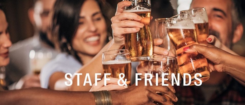 Eine Gruppe von Freunden und Mitarbeitern, die Biergläser erheben, lächeln und lachen in einer lebhaften Atmosphäre.