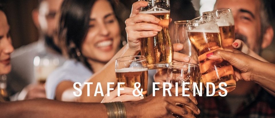 A group of people are gathered around a table, holding glasses of beer, smiling and clinking their glasses together. The text 'STAFF & FRIENDS' is displayed prominently above them.