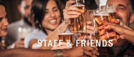 Eine Gruppe von Menschen, Mitarbeiter und Freunde, heben ihre Biergläser zum Anstoßen.