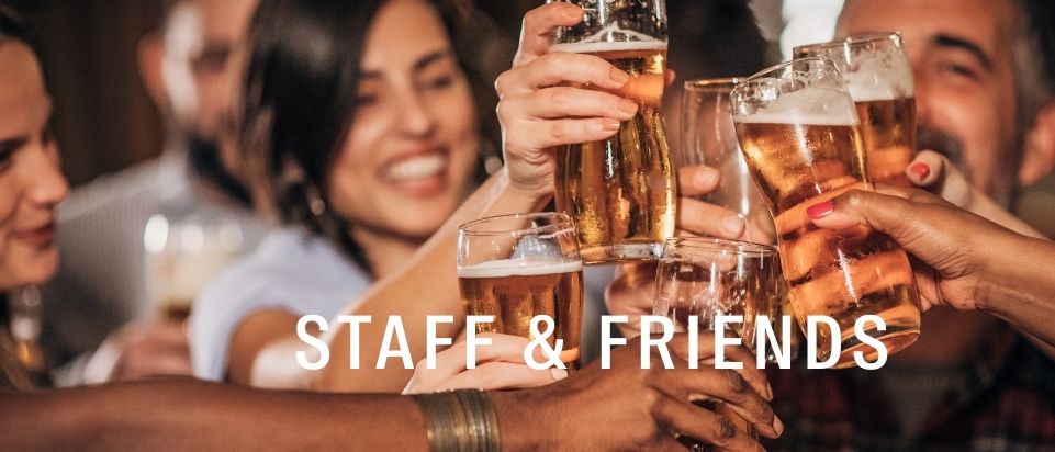 Eine Gruppe von Menschen, Mitarbeiter und Freunde, heben ihre Biergläser zum Anstoßen.