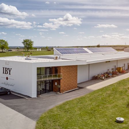 Bild enthält, Architecture, Building, Electrical Device, Solar Panels, Outdoors, Grass, Plant, Car, Wheel, Aerial View