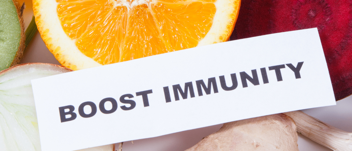 Verschiedene Obst- und Gemüsesorten sind in einem Kreis angeordnet, mit einer Karte in der Mitte, auf der steht Immunität stärken.