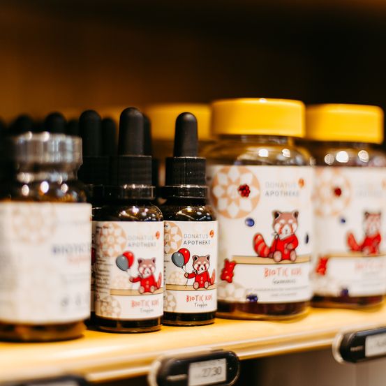 Eine Reihe von Biotic Kid Flaschen mit roten Panda-Illustrationen wird auf einem Regal präsentiert. Jede Flasche hat einen schwarzen Deckel.