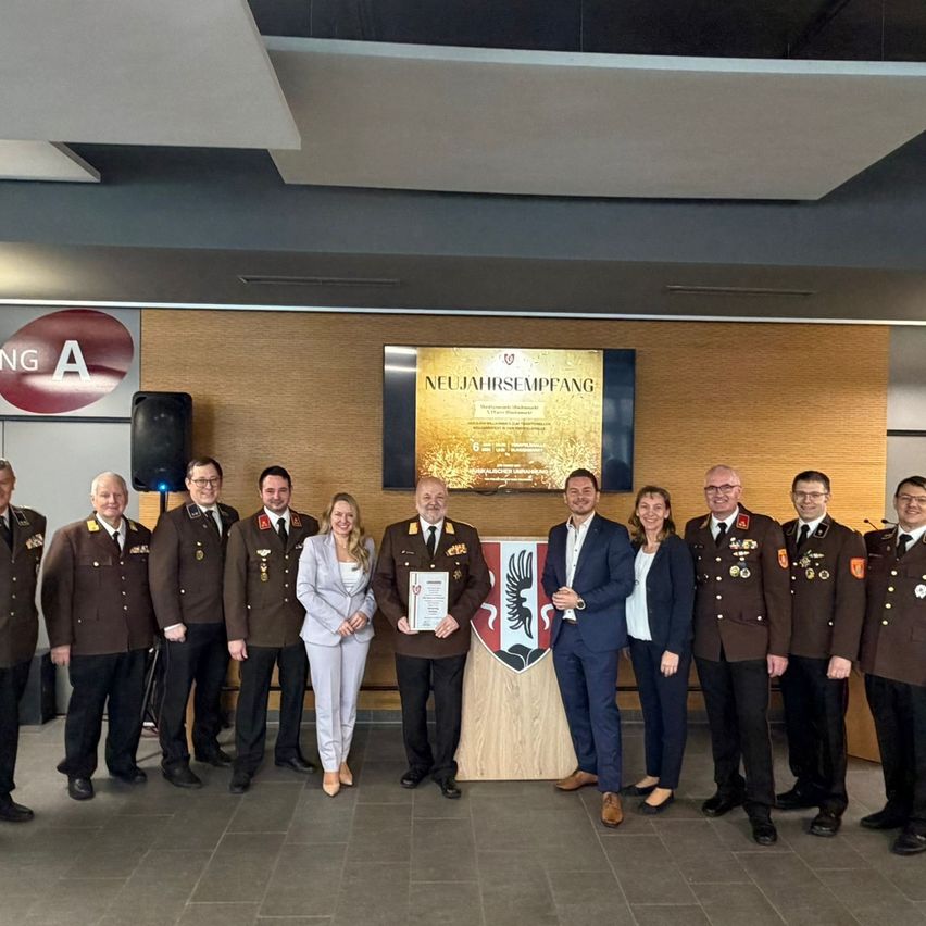 Eine Gruppe von Militäroffizieren und Personal posiert für ein Foto. Sie tragen alle Uniformen und scheinen sich in einer formellen Umgebung zu befinden.