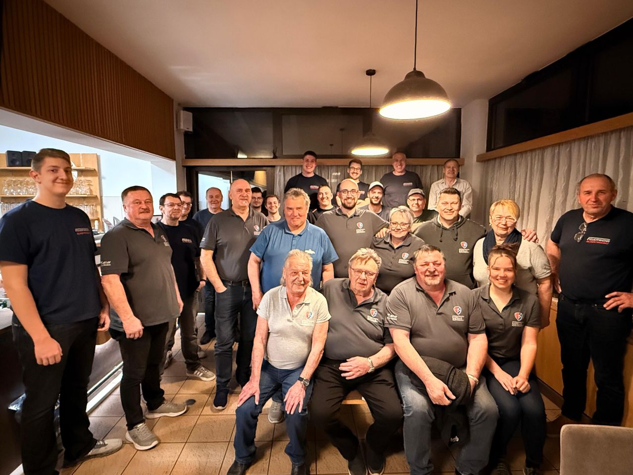 Eine Gruppe von Menschen in Uniformen, die lächeln, posiert für ein Foto in einem Raum.