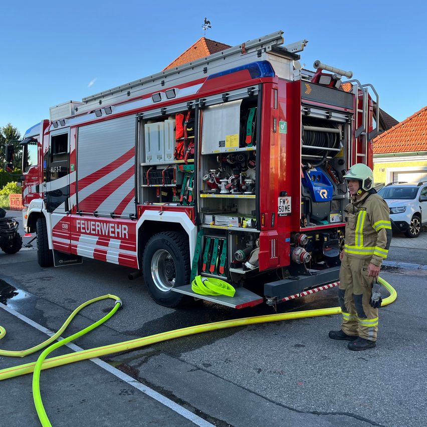 A firefighter is standing next to a fire truck with its back doors open. The truck is parked on the side of the road.