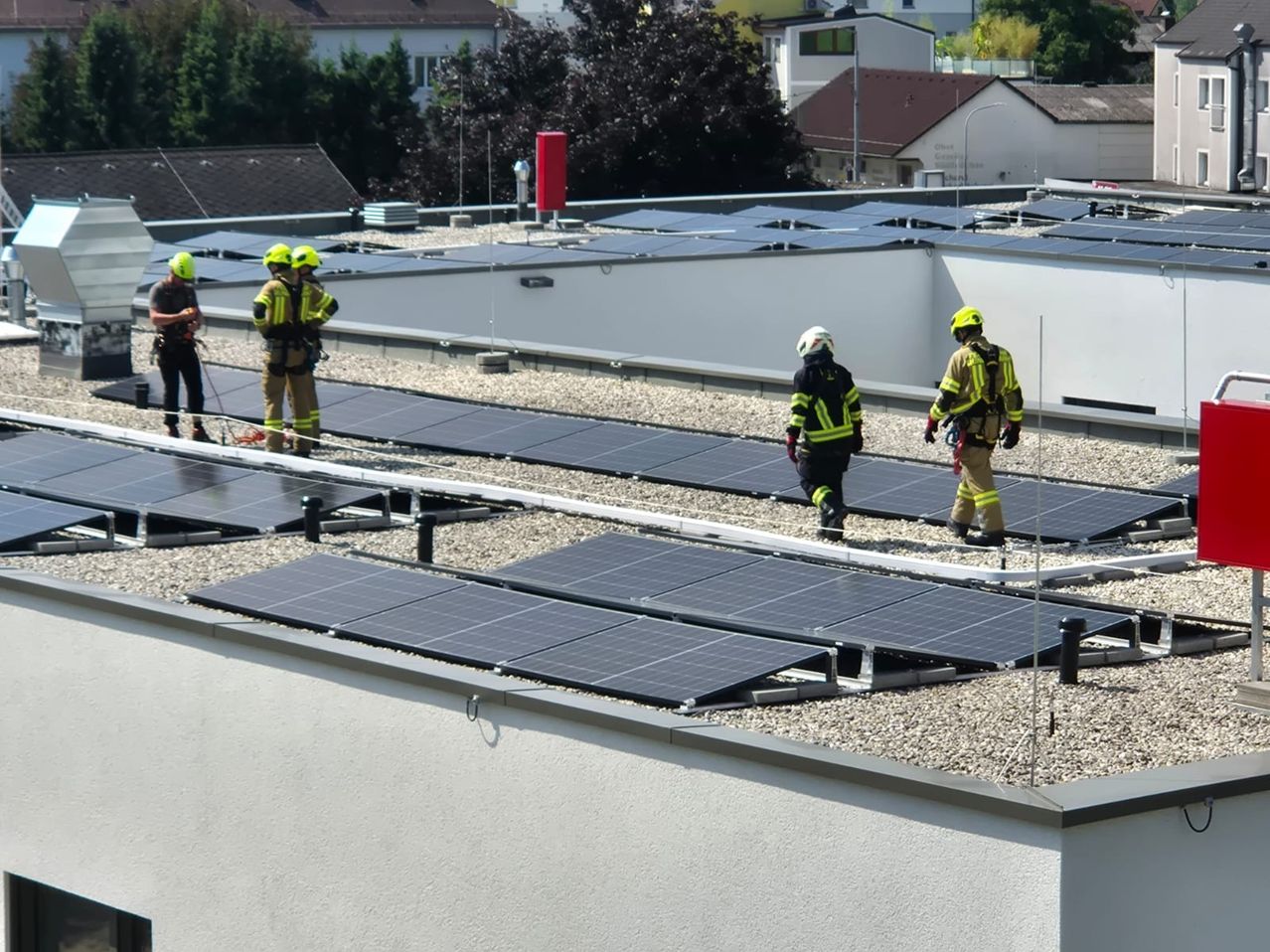 Feuerwehrleute in Schutzkleidung auf einem Dach mit Solarpanelen. Sie gehen herum und inspizieren das Gebiet.