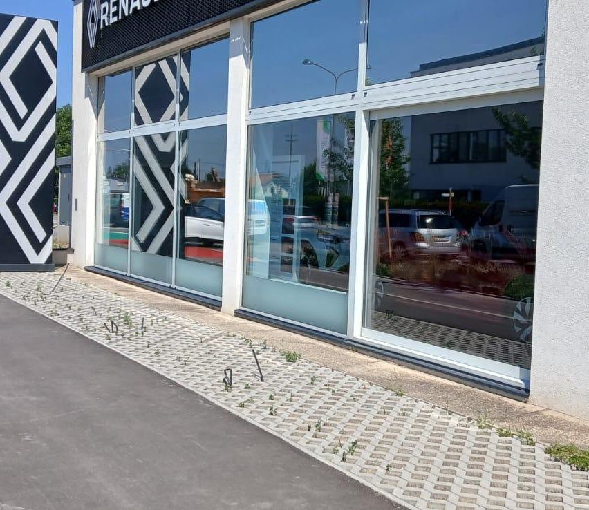 Ein modernes Renault-Autohaus mit Glaswänden und einem schwarzen und weißen Logo an der Vorderseite. Autos sind durch die Fenster sichtbar.