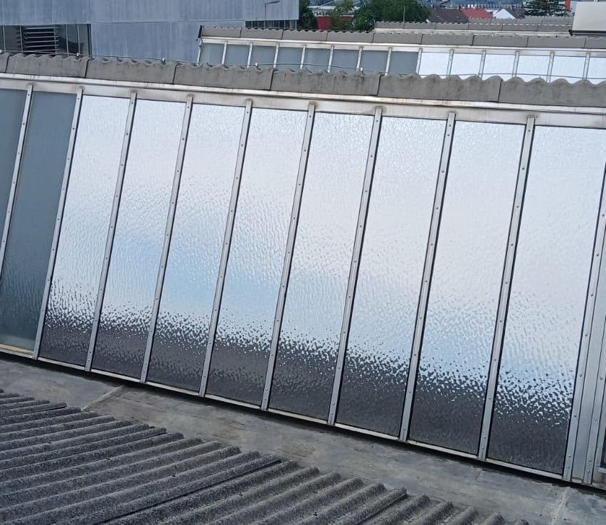 A close-up view of a modern building's rooftop with a series of reflective glass panels installed on the wall.
