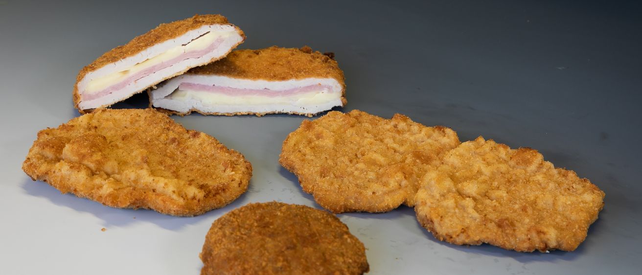 Eine Auswahl an frittierten Lebensmitteln wird auf einer weißen Oberfläche präsentiert. Dazu gehören zwei größere, gebackene Sandwiches ähnelnde Stücke und drei kleinere, runde, gebackene Stücke.