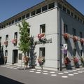 Ein graues Gebäude mit mehreren Fenstern hat Blumenvasen an der Außenwand. Es hat ein Schild mit dem Wort 'Floral' darauf. Vor dem Gebäude stehen Bäume und Pflanzen.