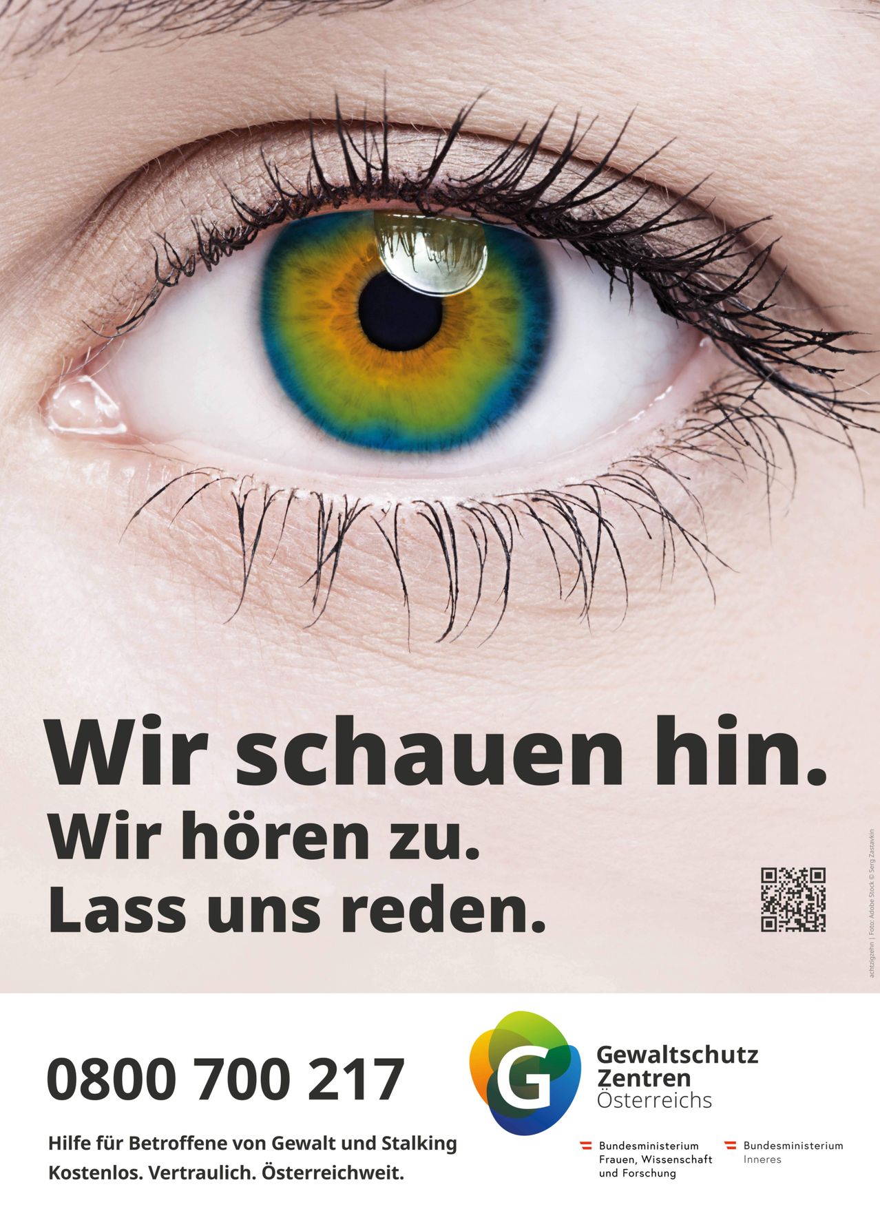 Nahaufnahme eines menschlichen Auges mit einem lebhaften blauen, grünen und gelben Iris. Unten am Auge steht: 'Wir schauen hin. Wir hören zu. Lass uns reden.' Unter dem Text ist ein QR-Code abgebildet.