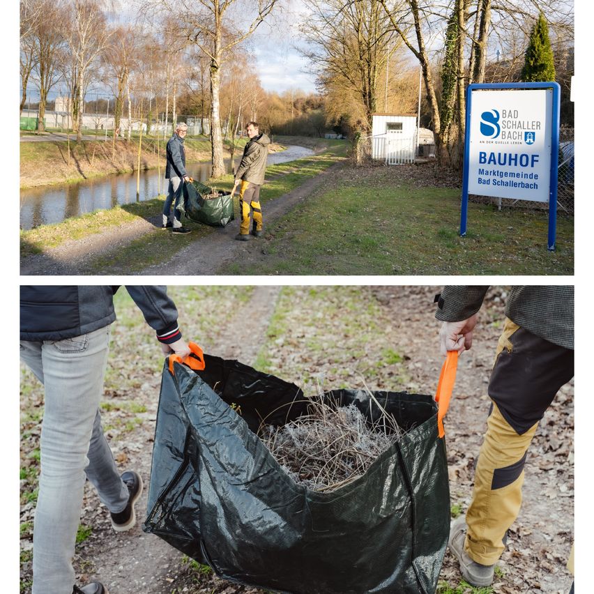 Zwei Personen sammeln in grünen Säcken trockene Zweige entlang eines Pfades an einem Fluss. Ein Schild steht 'Bauhof Bad Schallerbach'.