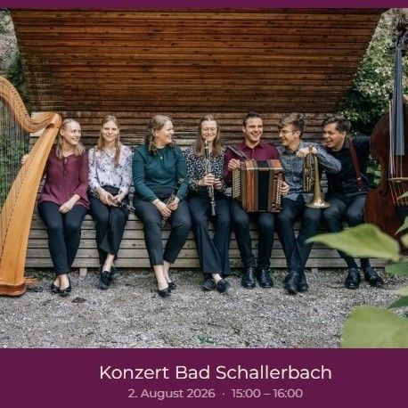 Eine Gruppe von Musikern sitzt auf einer Holzbank, lächelt und hält ihre Instrumente. Sie sind in formeller Kleidung gekleidet und von einer natürlichen Umgebung umgeben. Der Text am unteren Rand lautet 'Konzert Bad Schallerbach 2. August 2026 15:00 - 16:00'.