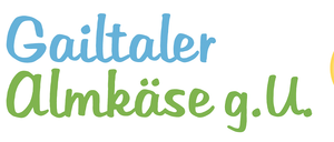 Das Logo zeigt 'Gailtaler Almkase' in blauem Text mit einem gelben Kreis, der ein Stück Kuchen enthält. Der Text 'Gailtaler Almkase' steht in Weiß auf dem Kuchenstück.