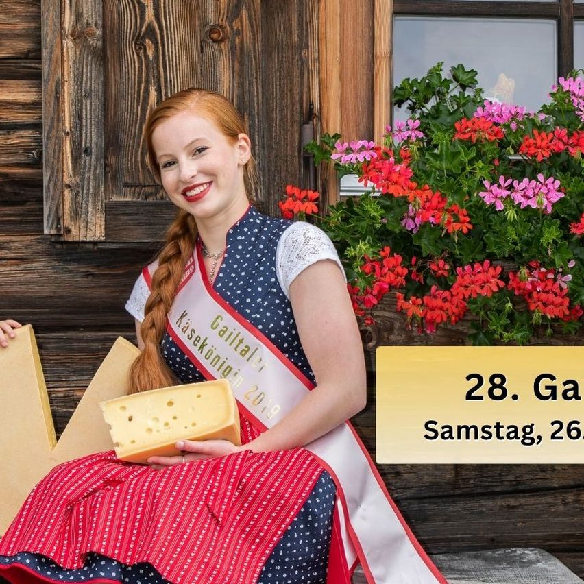 Eine Frau und ein Junge sitzen auf einer Holzbank vor einem Holzhaus. Die Frau hält ein Stück Käse und lächelt. Der Junge hält auch ein Stück Käse. Es gibt ein Fenster mit einer Pflanze auf der Fensterbank.