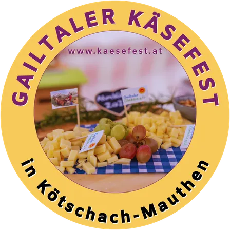 Rundes Logo für das Gailtaler Käsefest mit einer Auswahl an Käse, Trauben und anderen Lebensmitteln auf einem blau-weiß karierten Tischtuch. Die URL www.kaesefest.at ist ebenfalls angezeigt.