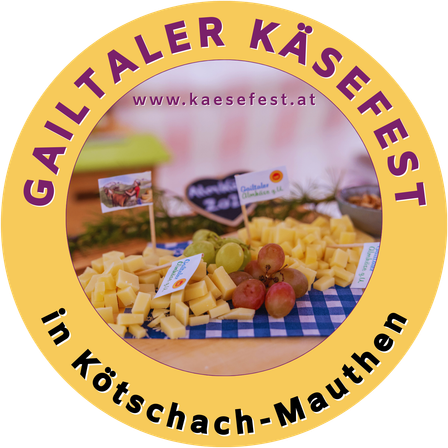 Rundes Logo für das Gailtaler Käsefest mit einer Auswahl an Käse, Trauben und anderen Lebensmitteln auf einem blau-weiß karierten Tischtuch. Die URL www.kaesefest.at ist ebenfalls angezeigt.