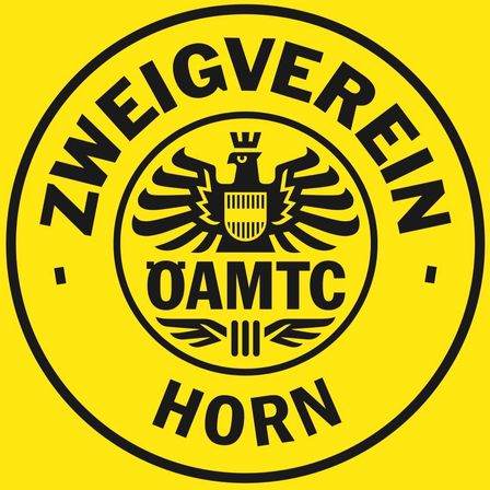 Ein gelbes rundes Emblem zeigt einen stilisierten Adler mit Krone und einem Schild auf der Brust. Die Worte 'ZWEIGVEREEIN OAMTC HORN' sind in Schwarz auf dem Emblem geschrieben.