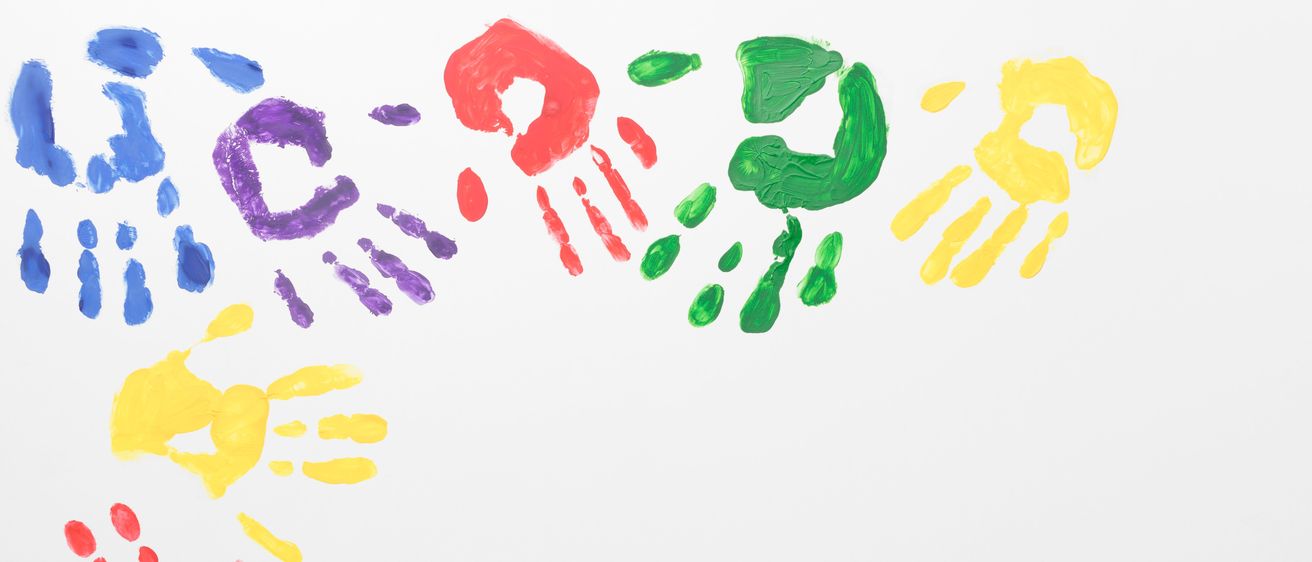 Eine farbenfrohe Anordnung von Handabdrücken, gemalt in Rot, Gelb, Grün, Blau und Lila auf weißem Hintergrund.