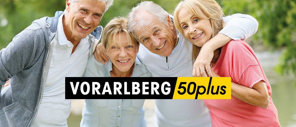 Vier lächelnde Erwachsene, zwei Frauen und zwei Männer, stehen eng beieinander in einer sonnigen Outdoor-Umgebung mit Bäumen im Hintergrund. Das Bild hat einen Textüberlagerung, der 'VORARLBERG 50plus' lautet.