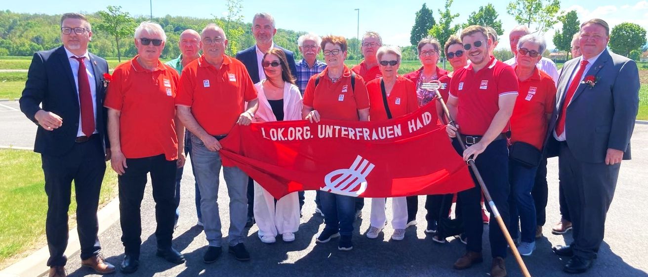 Eine Gruppe von Menschen in roten Shirts, die ein Banner mit der Aufschrift 'LOKORG. UNTERFRAUEN HAID' halten, posiert für ein Foto.